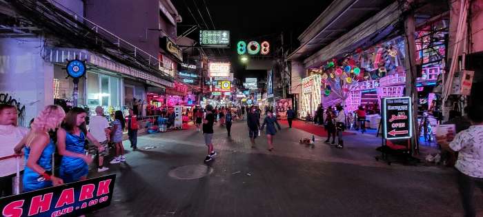 Crowds of people and bright neon signs at night time on Walking Street in Pattaya, Thailand